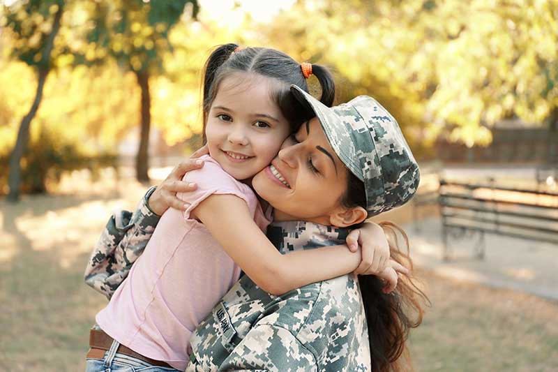 a little girl hugging her veteran mom in uniform